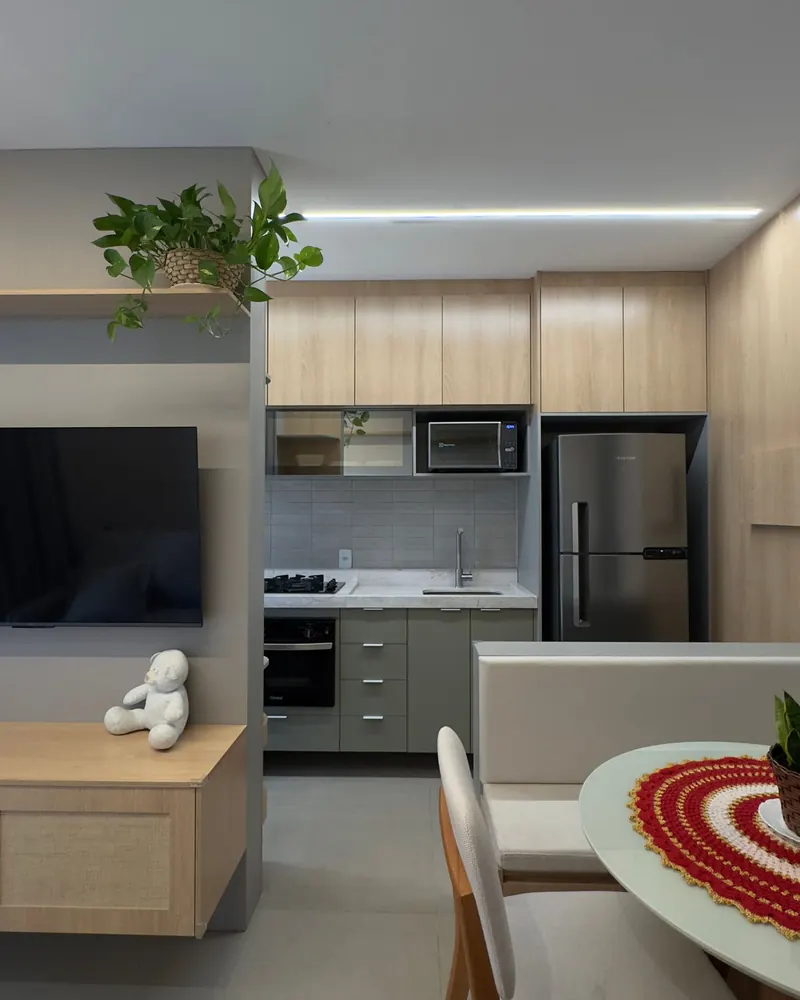 Cozinha e sala integradas de apartamento, com marcenaria clara